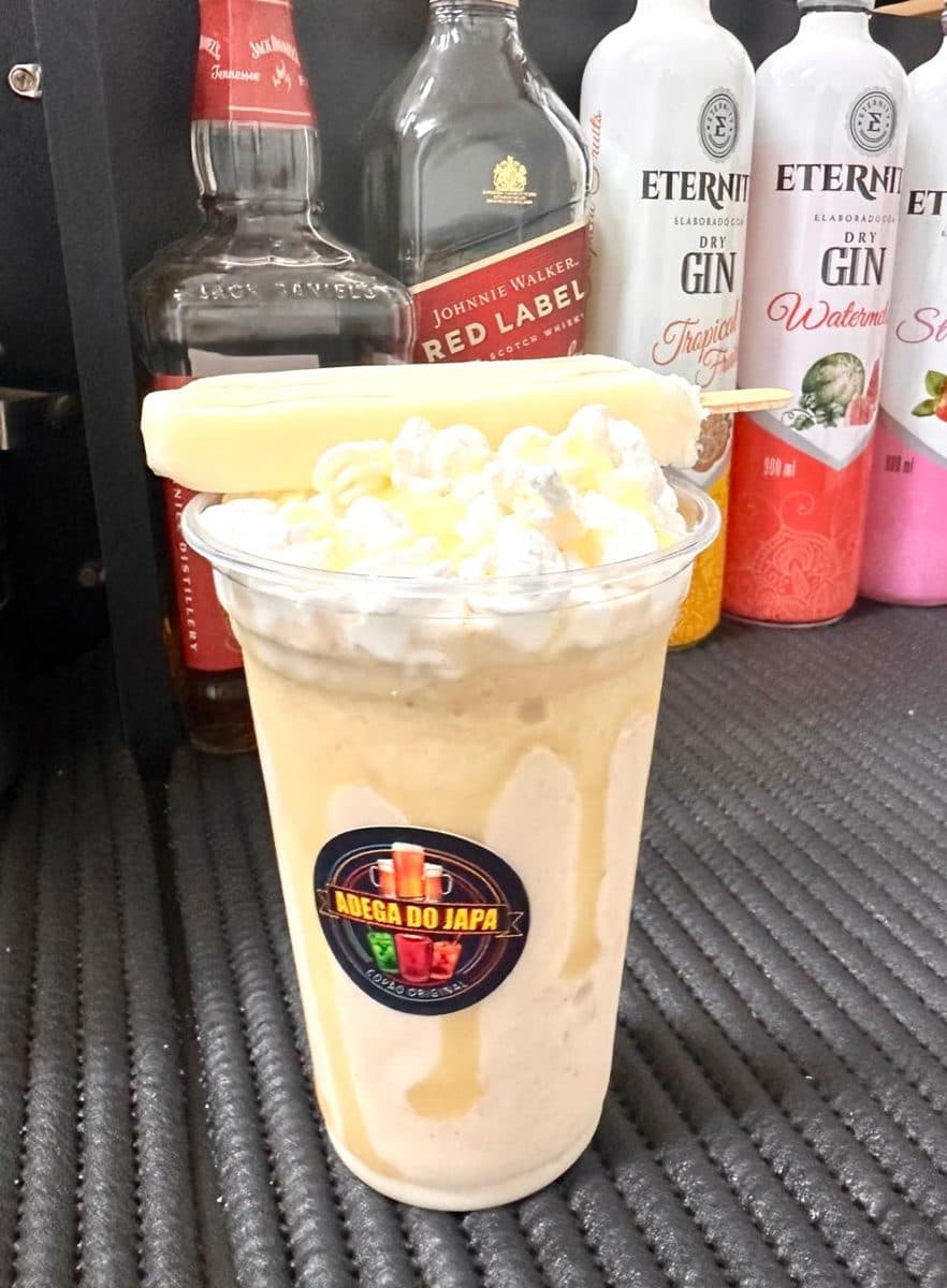 Copão cremoso com chantilly e picolé branco, com garrafas ao fundo